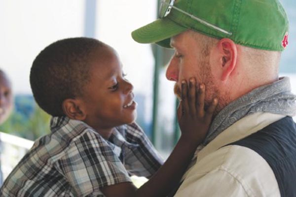  Trinity EMS EMT Dave Roberts, of Tyngsboro, is warmly greeted by a Haitian child at an orphanage during a recent mission to that island nation.