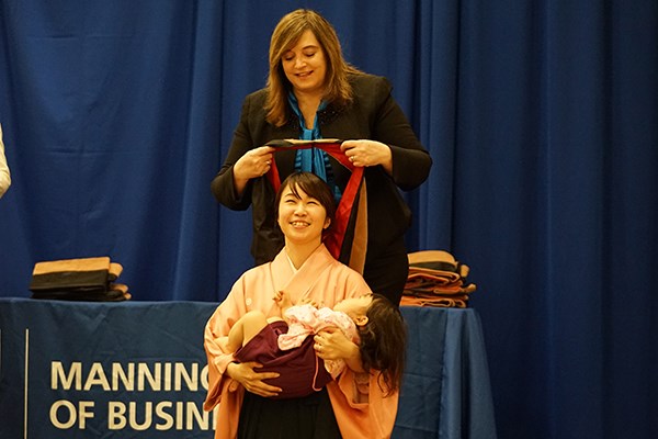Tomoe Yashida holds her daughter as Dean Sandra Richtermeyer placed a ceremonial hood over her head