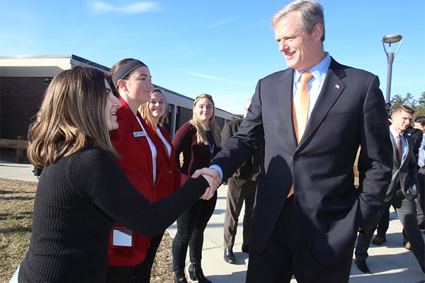 Charlie Baker shakes hands with female student