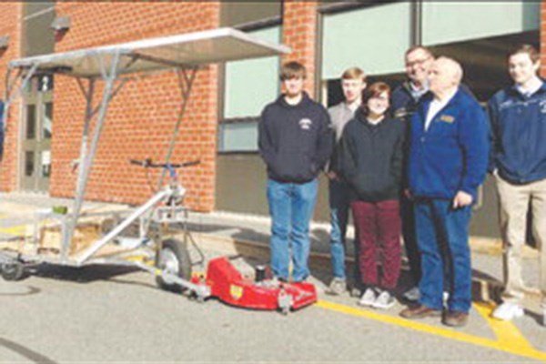 Students and teachers stand with solar mower