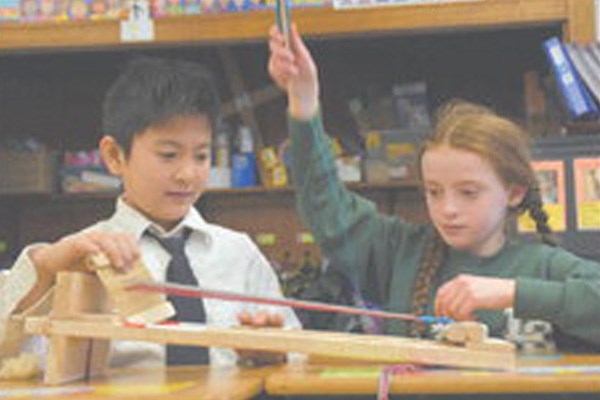 Lowell Catholic third-graders Tyson Pham and Irene Early operate a small weaving loom