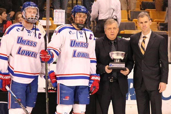 UMass Lowell players A.J. White and Michael Kapla, and head coach Norm Bazin, right, accept the Hockey East runner-up trophy from Hockey East Commisioner Joe Bertagna Saturday night.