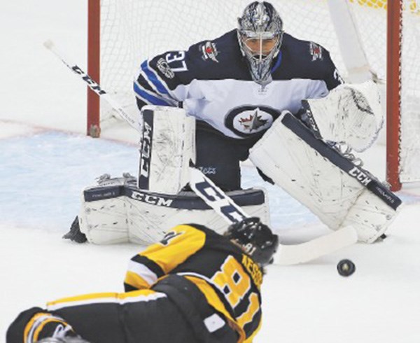  Winnipeg Jets goaltender Connor Hellebuyck prepares to make a glove save on Penguins star Phil Kessel.