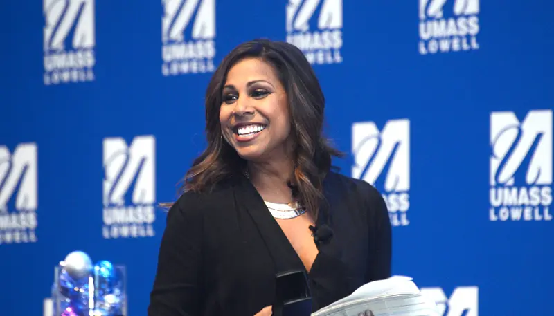 Taniya Nayak speaks at UML in front of a blue backdrop about interior design