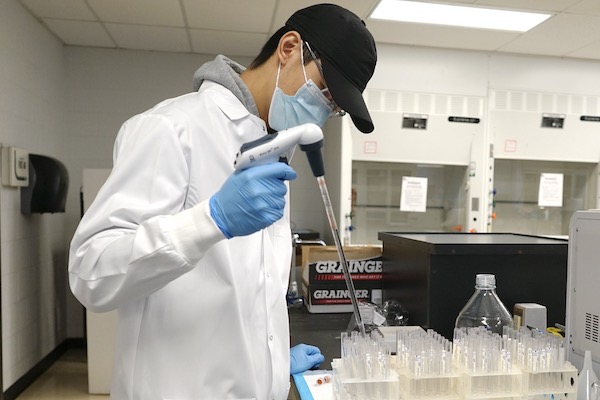 Lab worker Brendan Leung fills tubes with a saline solution