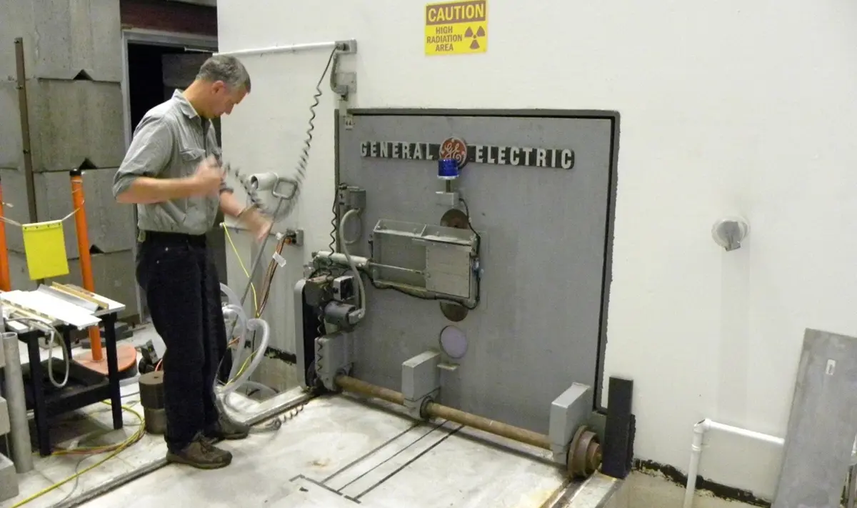 Person in front of door, with “General Electric” on it. The door is mounted on wheels on a track on the floor. 