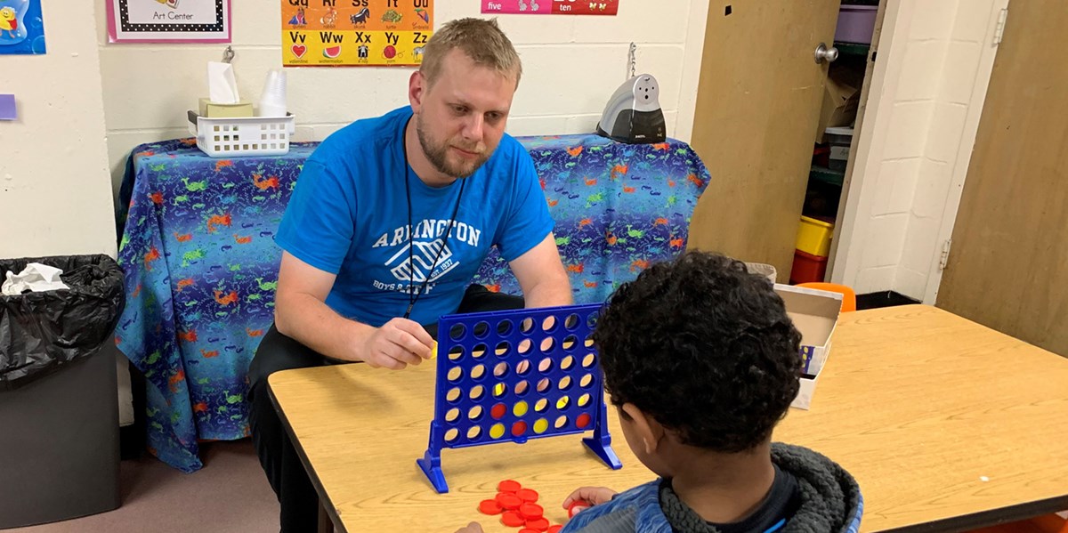 Thomas Baldwin plays Connect 4 with a child at the Boys & Girls Club 