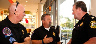 UMass Lowell police officers talk with a city of Lowell police officer during the “Coffee with a Cop” event at University Crossing.