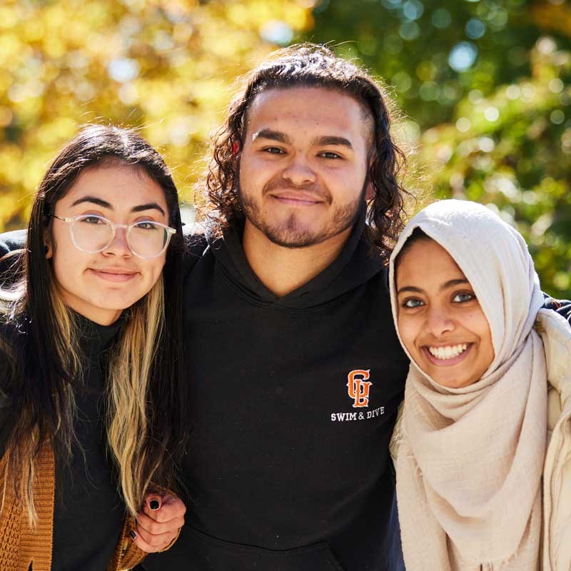 Three students pose and smile