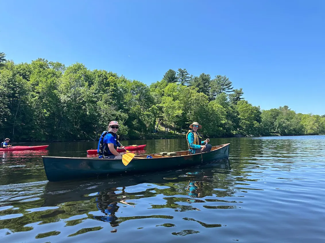 two people smile while floating in a green canoe on a sunny day