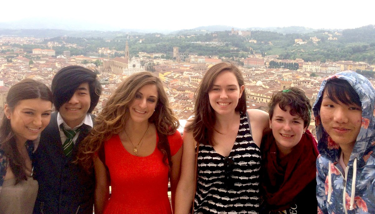 Six Umass Lowell art students, posing in front of a city in a foreign country. 