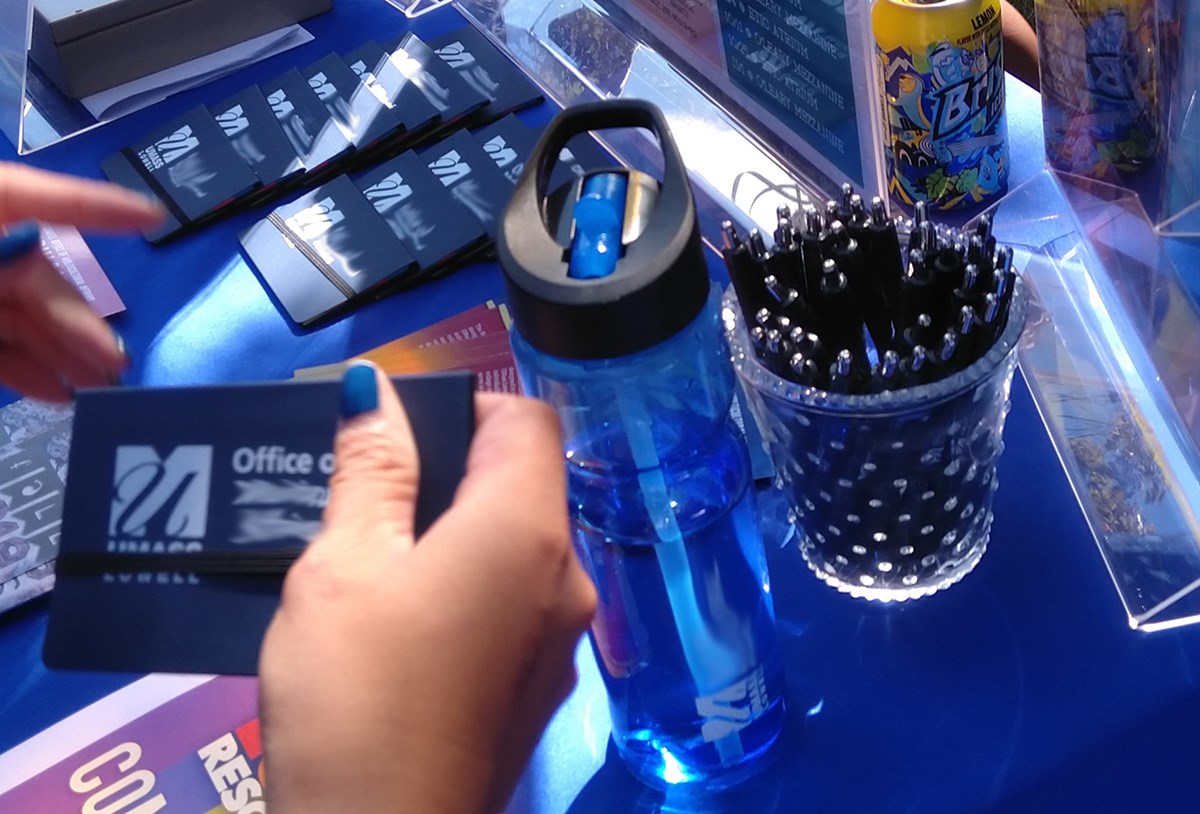 A table displaying UMass Lowell branded swag including: water bottles, wallets, pens and more.