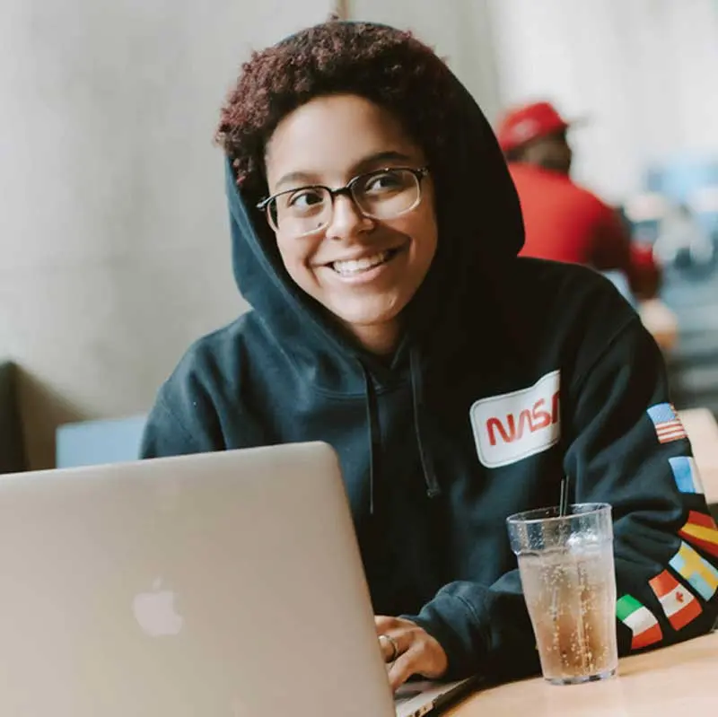 Student smiling while working on a laptop