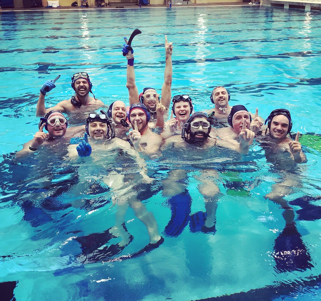 The UMass Lowell underwater hockey team, FloMass, in the pool signing #1 with their hands after winning the 2018 USA Underwater Hockey National Championship