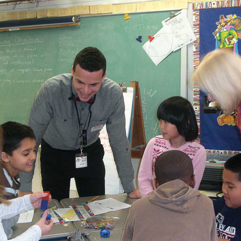 A UMass Lowell UTeach student interacts with students in a classroom. 