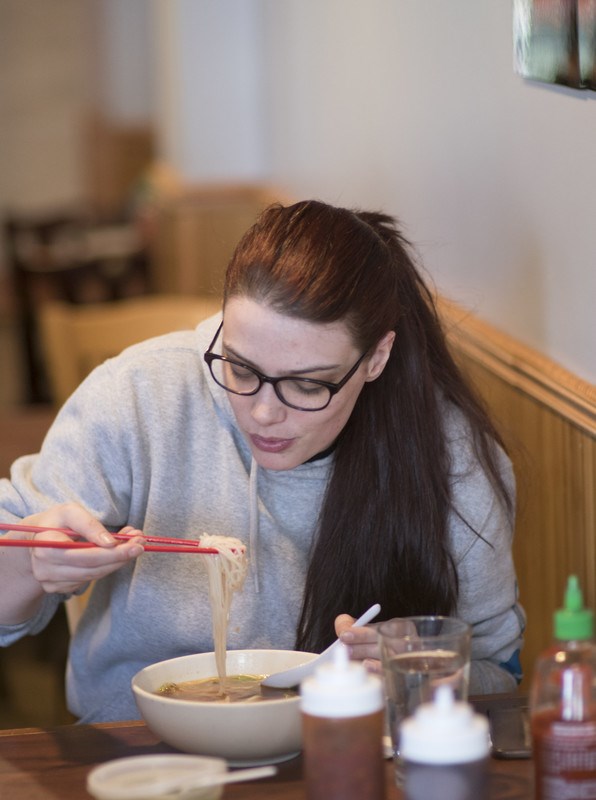 A young woman eats pho inside Viet Thai in Lowell, MA