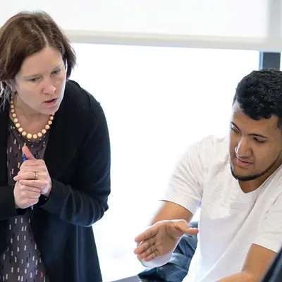 Woman standing looking at material that young man is discussing