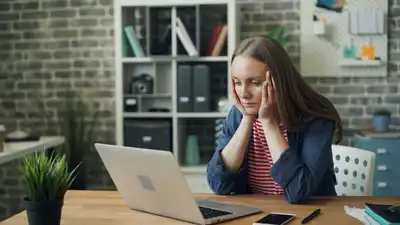 Person looking stressed sitting at table with laptop.