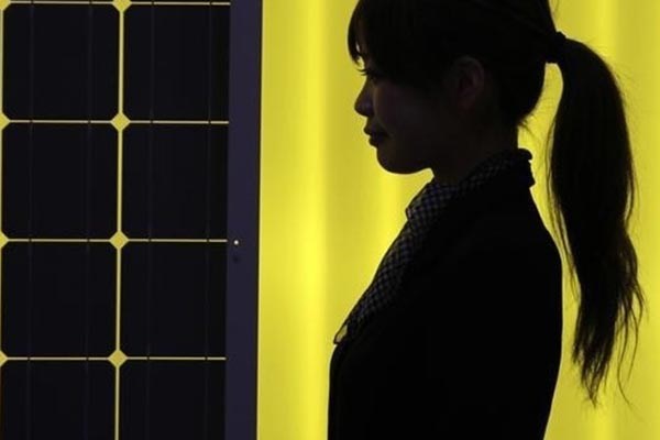 A woman is silhouetted next to a solar panel display.