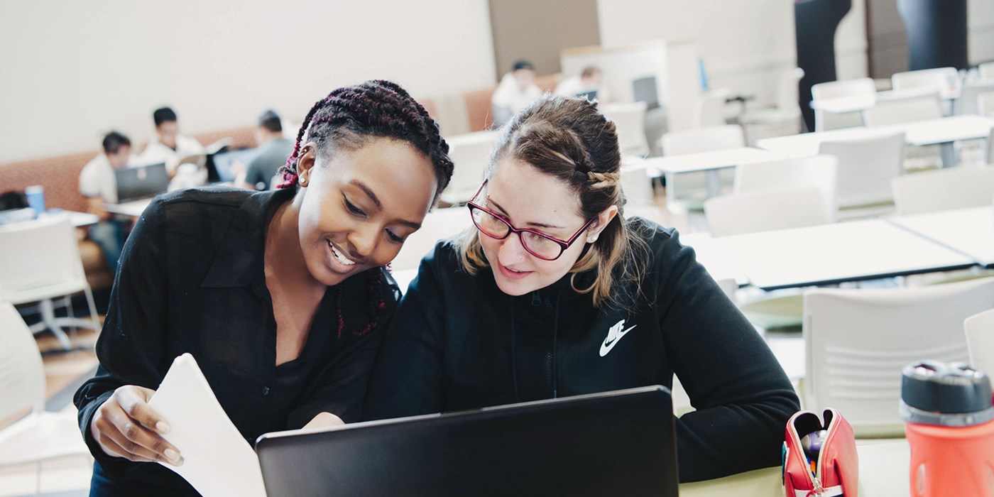 Two female students work together on a laptop