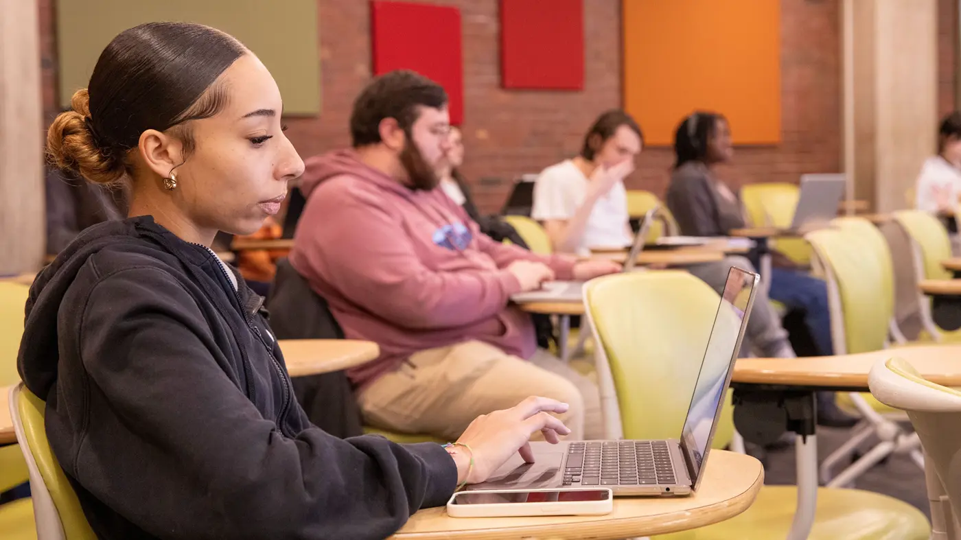 A student works on a laptop in a UMass Lowell classroom.