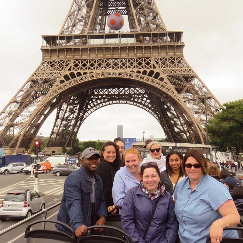 A group of students pose in front of the Eiffel Tower. 