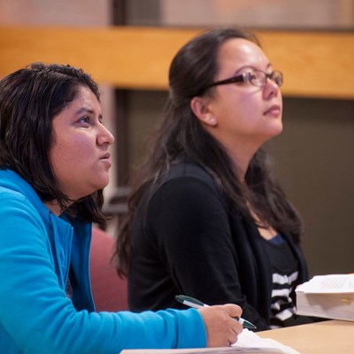 Two students listening to a presentation at a Writing Center event