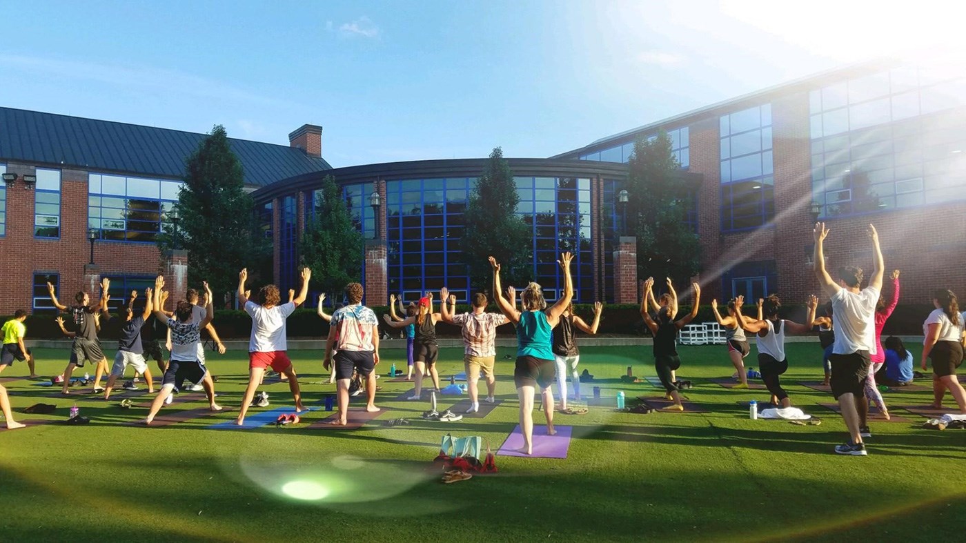 A group yoga class on the lawn in front of the Campus Recreation center.