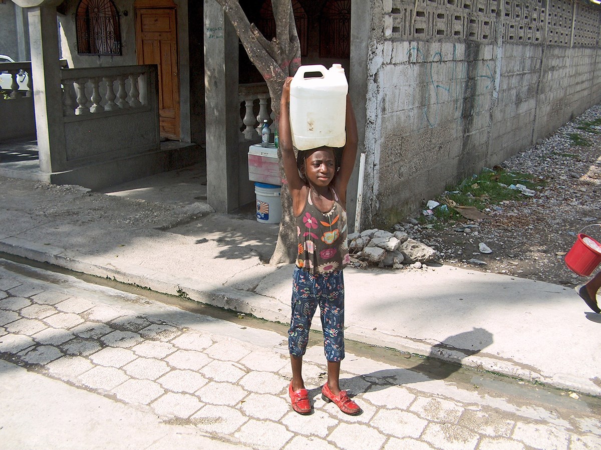 A young girl fetches contaminated water from a community well in Les Cayes, Haiti in 2013.