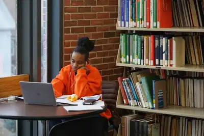 woman works on laptop at table in library