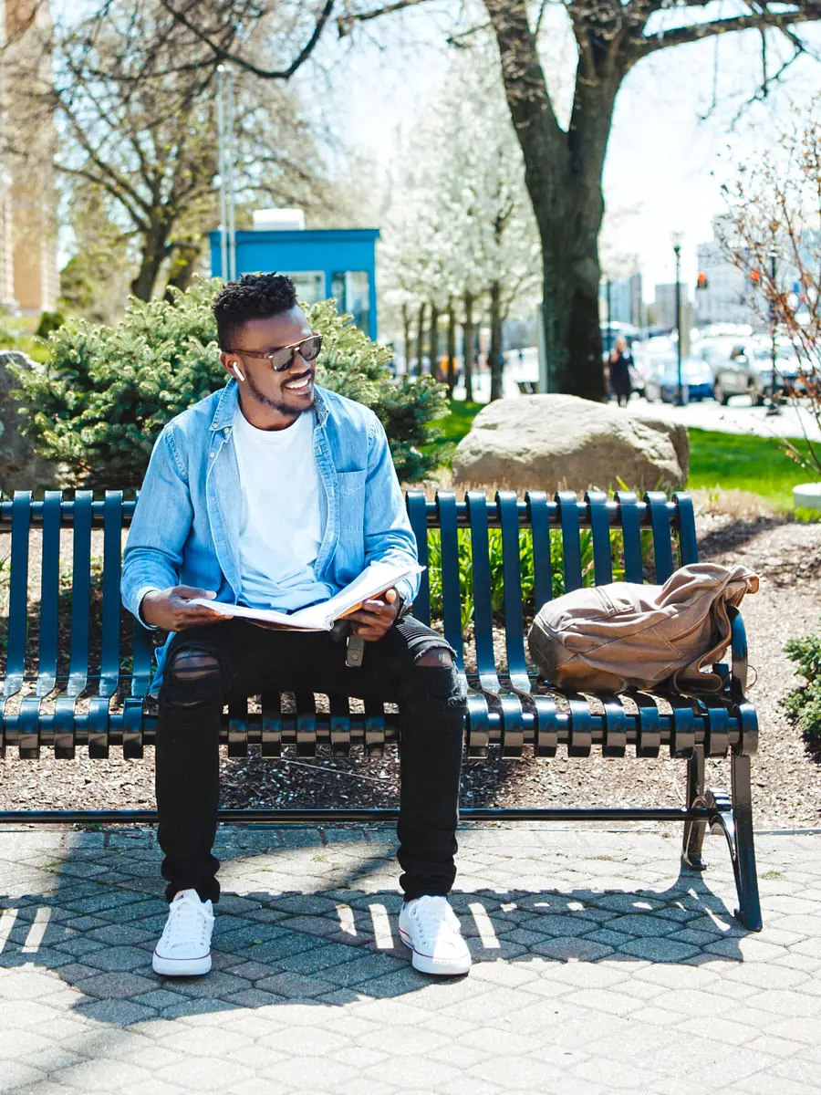 A student sitting on a bench with a book