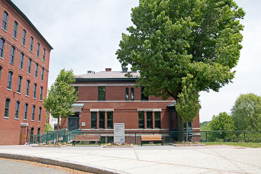 Charles Hoff Alumni Center showing benches and trees in front of red brick building