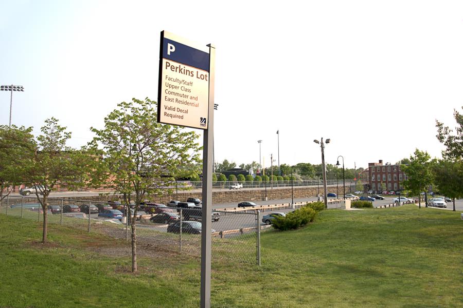 Parking sign for Perkins Lot in foreground with paved surface lot in background