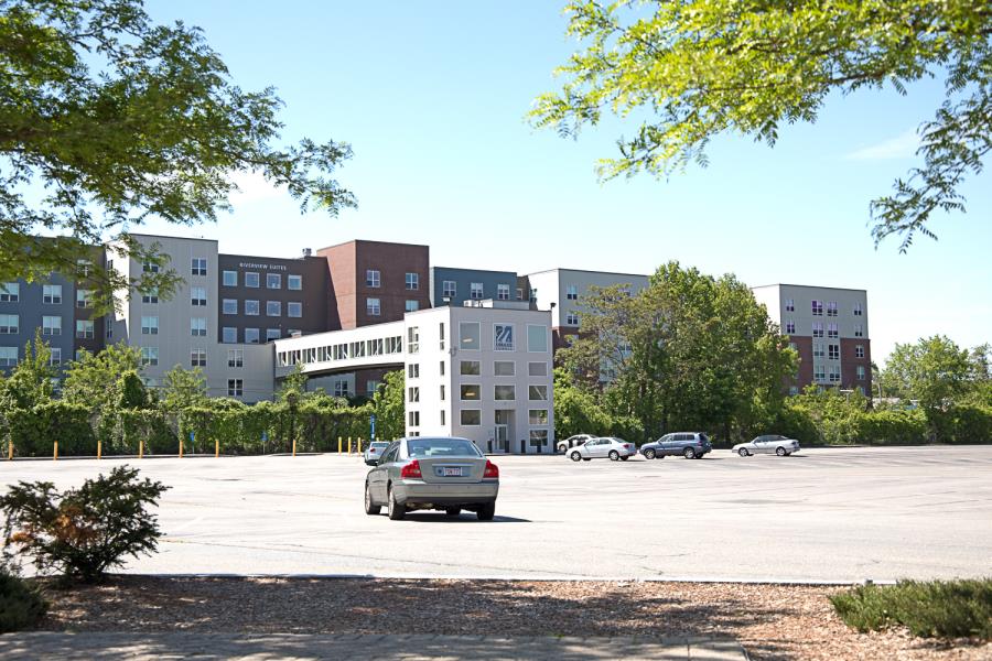 View from parking lot of multicolored Riverview Suites complex and elevated walkway over railroad tracks
