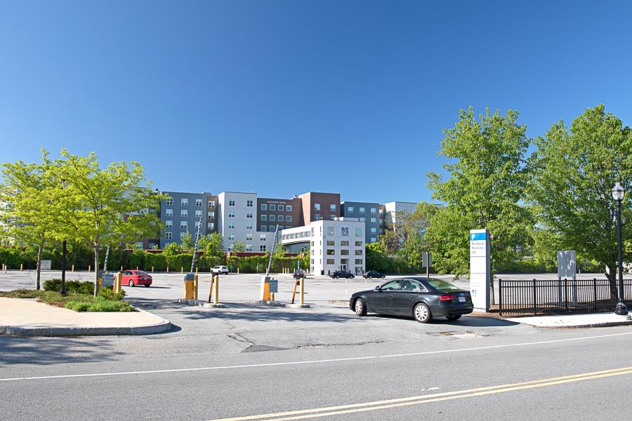 Gated entrance to large surface lot with Riverview Suites building in background