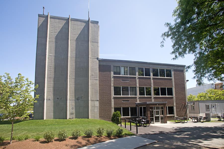 Three-story red brick building front, alongside five-story concrete structure
