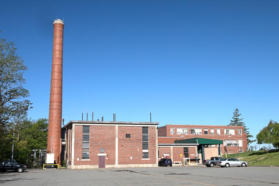 Tall red brick smokestack alongside two-story brick building