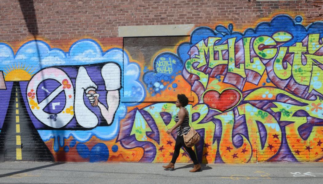 Woman walks by mural on side of brick building on Decatur Way.