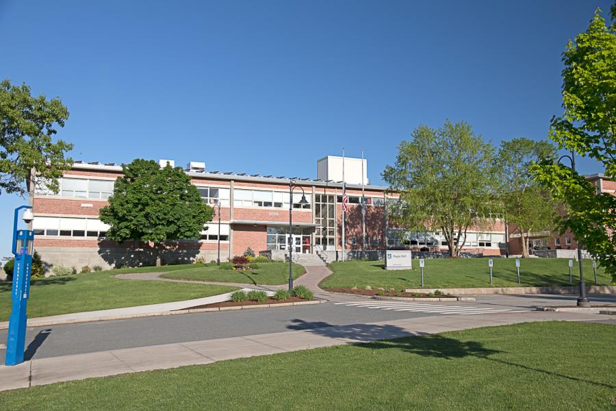 Multilevel brick and glass classroom building with walkways, grass and trees in foreground.