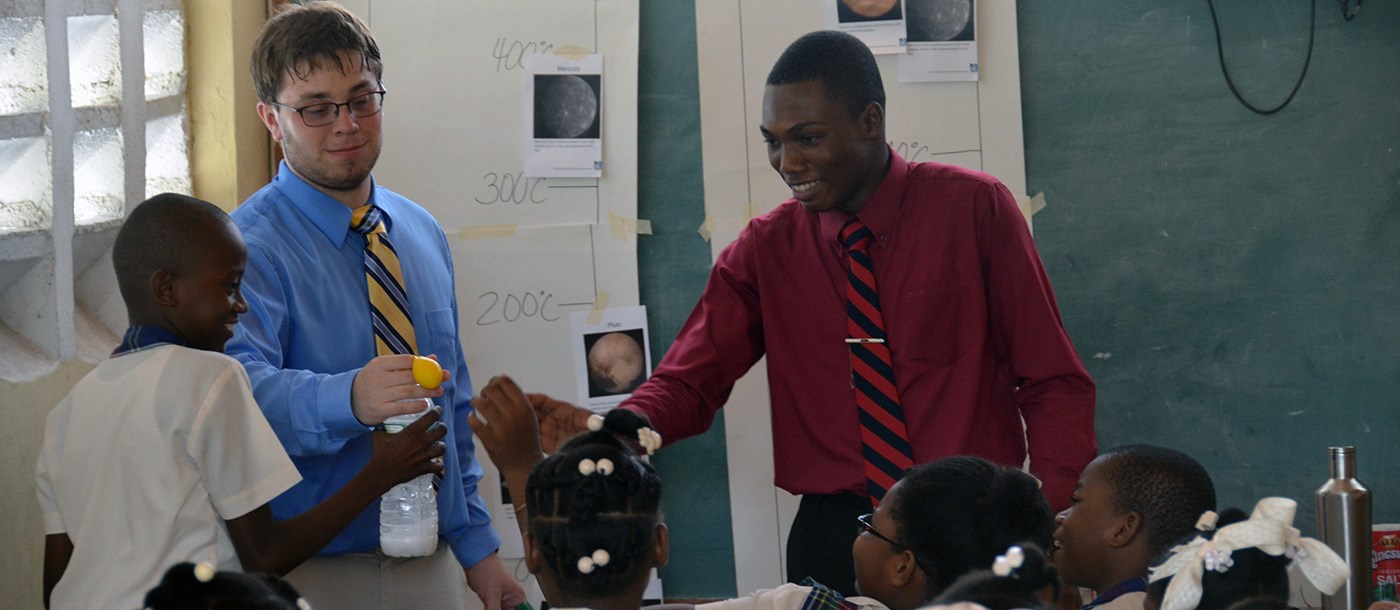 Two UMass Lowell male students doing a science demonstration for a classroom full of young Haitian children on a visit to Haiti in 2016.