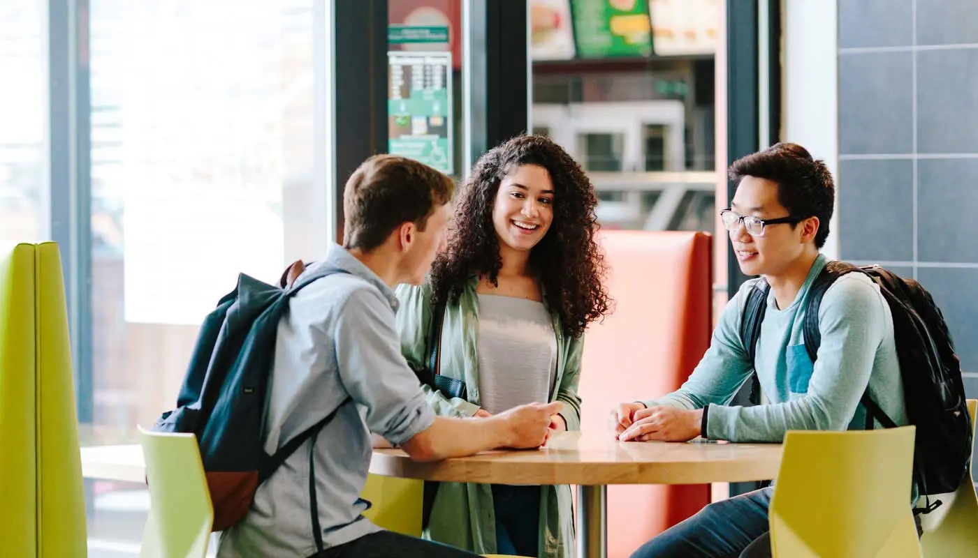 Three students talking at a round table